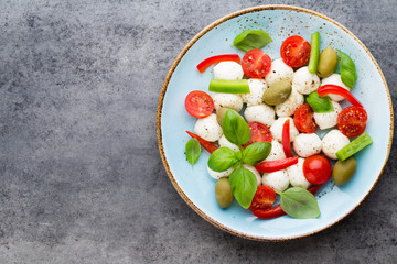 Delicious caprese salad with ripe cherry tomatoes and mini mozzarella cheese balls with fresh basil leaves.