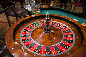 Casino, gambling and entertainment concept - roulette table and stack of poker chips