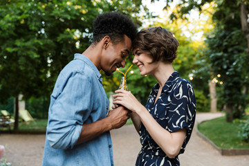 Young loving couple outdoors in park having fun drinking soda together.