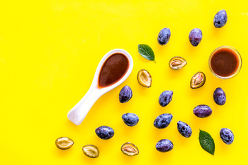 Fresh tkemali sauce. Traditional caucasian, georgian sauce or plum jam in spoon near plums on yellow background top view space for text