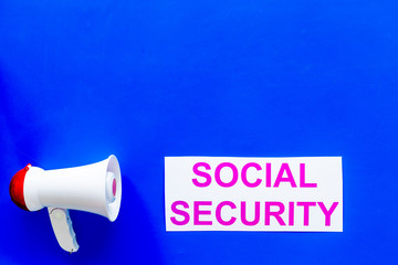 Social security concept. Printed words social security near megaphone on blue background top view copy space