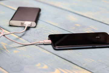 mobile phone and spare battery for charging on a wooden vintage background