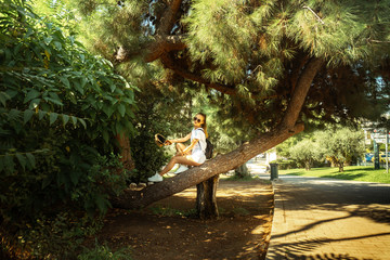 young beautiful girl sitting on a tree