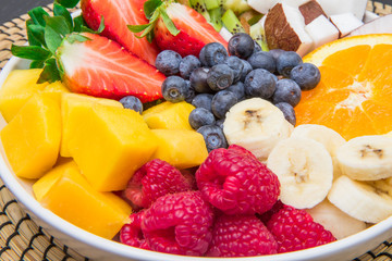 fruit salad with fresh berries, orange,  coconut, mango, and sliced of banana