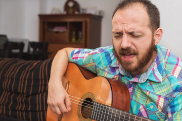 Young man musician playing acoustic guitar