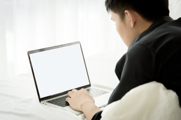 Asian worker man has working with laptop before start work on bed in the morning.