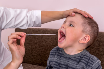 Doctor pediatrician examining throat of little boy