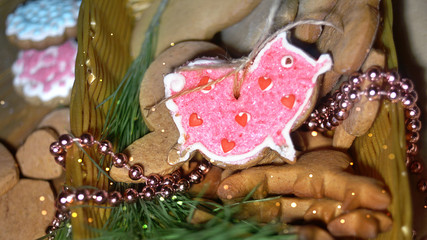 Fototapeta na wymiar Christmas or New Year still life with cookies in a basket in the form of a pink pig, the symbol of the year. on the background of Christmas trees and garlands. Close-up.