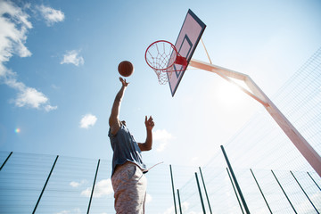 Fototapeta premium Low angle action shot of African man jumping in basketball court scoring points, copy space