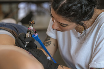 Young woman tattooing on the ribs.