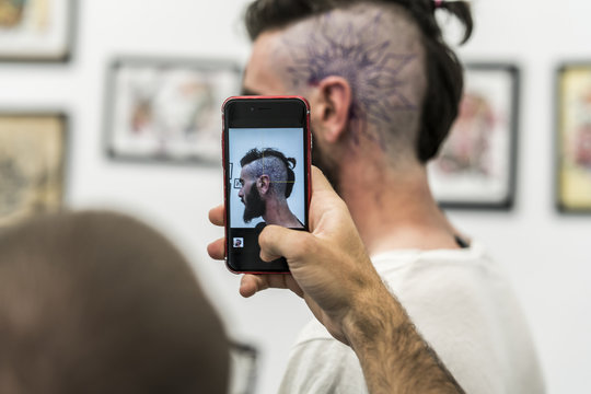 Portrait with the cell phone to the drawing of the tattoo on the head.