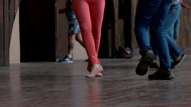 Close up legs of dancing people indoor. Rustic wooden floor.