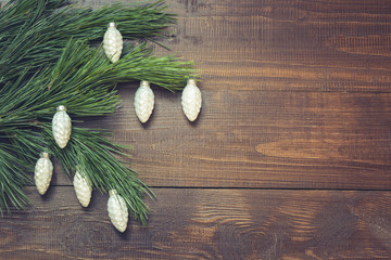 Christmas tree branches with white cones balls on wooden background. Top view. Copy space.