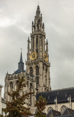 Fototapeta na wymiar Antwerp, Belgium - September 24, 2018: Closeup of Towers and nave of Onze-Lieve-Vrouwe Cathedral of Our Lady in back under gray cloudy sky. Some green foliage.