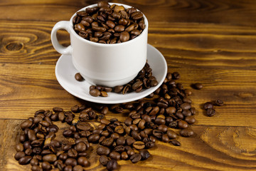 Coffee beans in white cup on wooden table