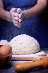 The baker is clapping hands covered with flour over the yeast dough