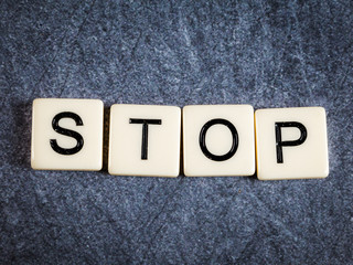 Letter tiles on black slate background spelling Stop