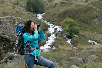 Naklejka premium A woman photographs the landscape in the mountains.
