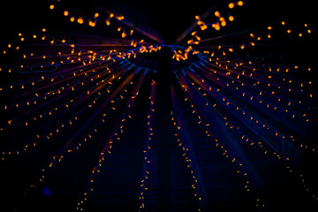A collection of small little orange lights on the top of a purple ceiling of a tent at a wedding at night in the UK