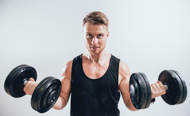 Handsome muscular man working out with dumbbells.