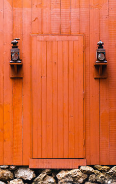 Old orange and red Western door between two old lanterns 