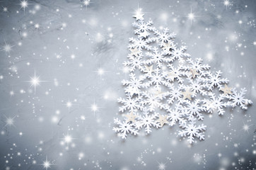 Decorative snowflakers laid in the form of a Christmas tree on a gray background.