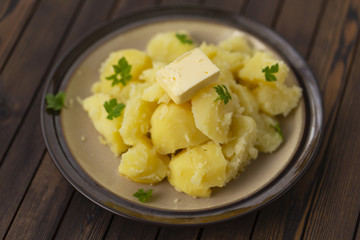 Fototapeta na wymiar Boiled potatoes with fresh herbs and oil in a bowl on a wooden table