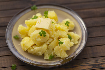 Boiled potatoes with fresh herbs and oil in a bowl on a wooden table