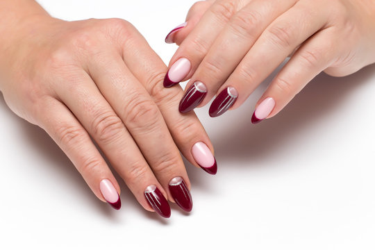 Burgundy French manicure with silver drawings, stripes on long sharp nails close-up on a white background  