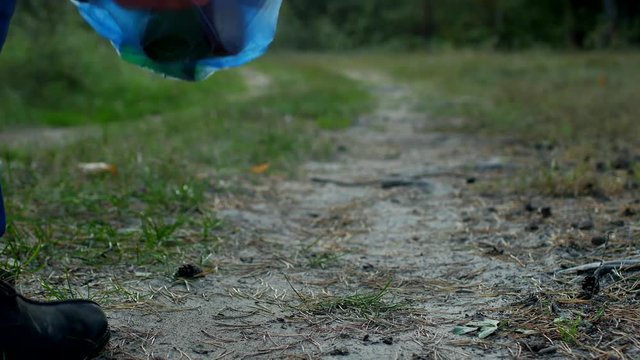male janitor cleaner in signal orange vest cleans garbage in the forest, close-up