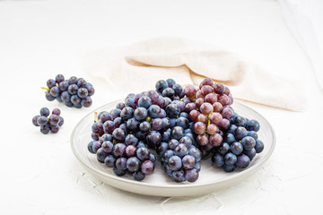 Berries of ripe blue grapes on a plate on a table. Harvesting in autumn