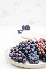Berries of ripe blue grapes on a plate on a table