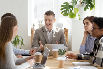 Five multiracial millennial diverse business team businesspeople colleagues sitting at meeting briefing in office boardroom. Happy company owner boss leader talk about improvement sales or good news