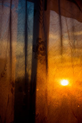 Through the curtain shines the setting sun