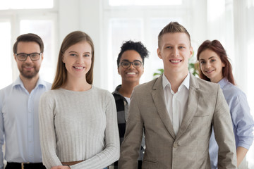 Obraz premium Group young millennial multiracial students business people professionals company staff standing together looking at camera. Five attractive smiling workers in office. Successful diverse team concept