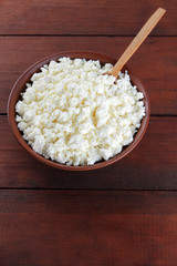 Cottage cheese. Cottage cheese on wooden boards. Soft cheese in earthenware dish. Milk product with wooden spoon. Copy space