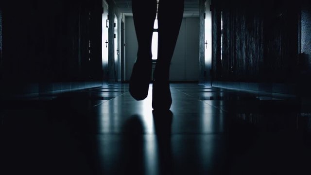 Close-up of silhouette of women's shoes with high thin heels of woman&rsquo;s heels during walk down corridor. Light at the end tunnel. Exit from difficult situation. Solving business issues and problems.