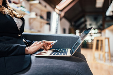 Close-up image of female person using laptop and credit card for online shopping.