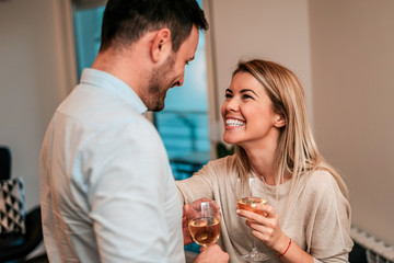 Celebrating an event or good news. Happy couple drinking white wine.
