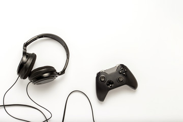 Black headphones and a gamepad on a white isolated background. Concept of the game on the console or computer. Rest after work. Cybersport. Flat lay, top view
