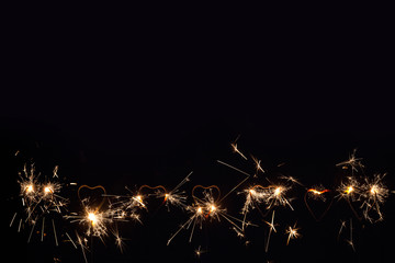 A lot of heart shape burning sparklers, isolated on black background. Birthday party background....