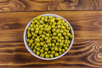 Bowl with canned green peas  on wooden table. Top view