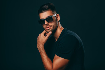 Handsome man with sunglasses posing in studio on dark background