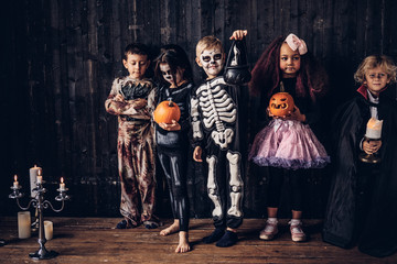 Group of children in costumes during Halloween party in an old house.