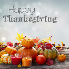 Fall harvest of pumpkins with leaves and candles on wooden table, copy space on fall gray sky background with happy Thanksgiving Day greetings