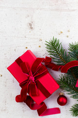 Christmas gift giving flat lay scene - christmas present box wrapped in red on white wooden table