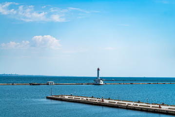view of the pier to the sea on the background of the lighthouse in the summer. Beautiful landscape
