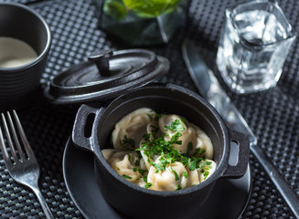 Traditional russian pelmeni, ravioli, dumplings with meat on black concrete background. Top view.