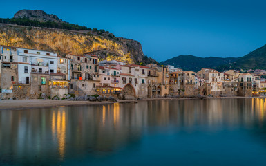 Fototapeta na wymiar Cefalù waterfront in the evening, with lights reflecting on the water. Sicily, southern Italy.
