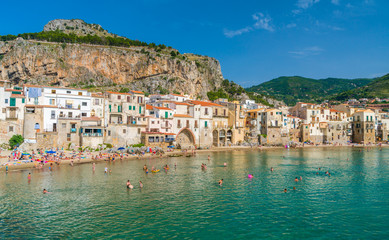 Cefalù waterfront with peole relaxing on a sunny summer day. Sicily, southern Italy.